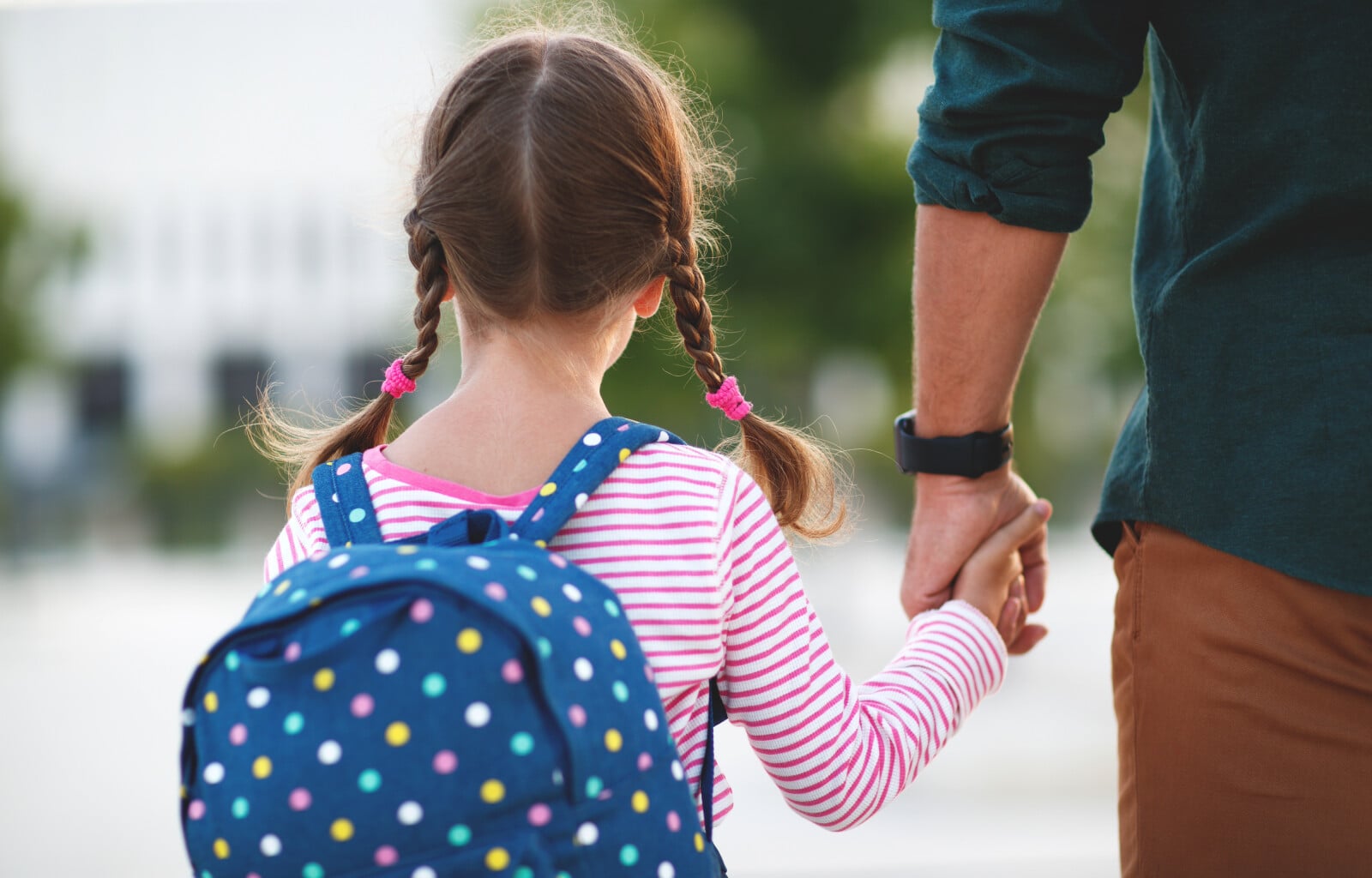 Parent holding a kids hand looking in the opposite direction