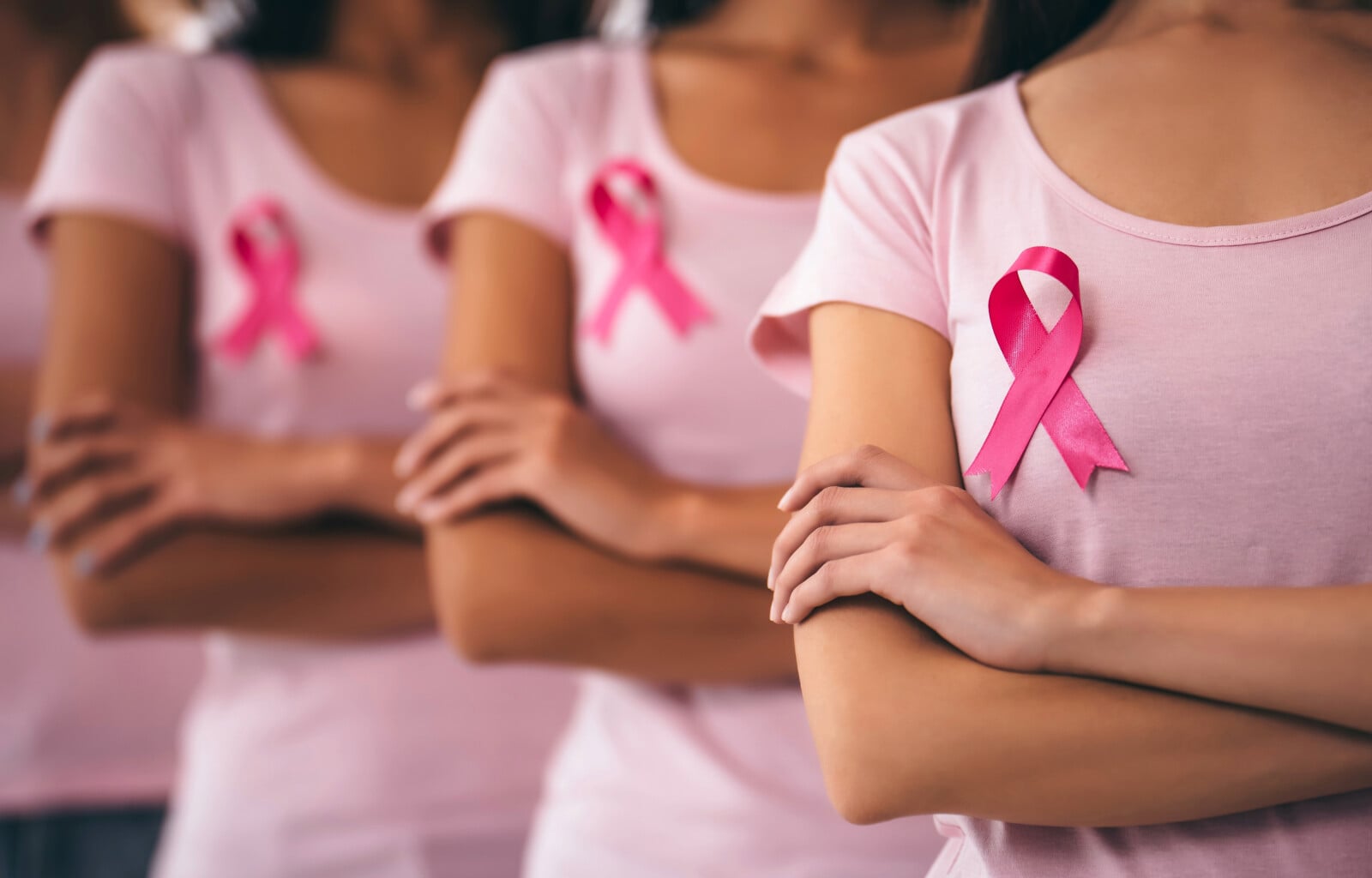 breast cancer awareness - 3 women in a line with a breast cancer ribbon on each of their shirts