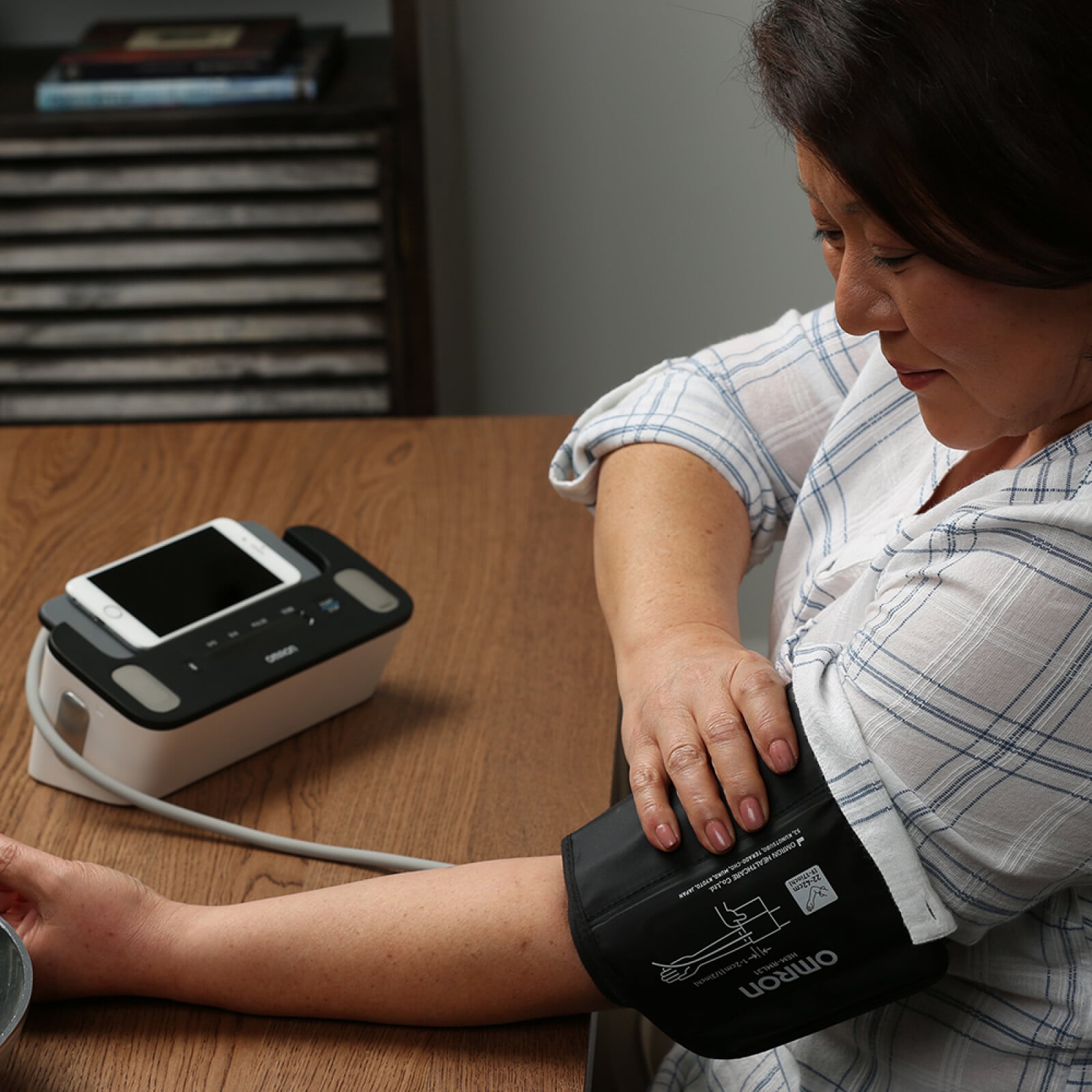 woman putting blood pressure cuff on arm