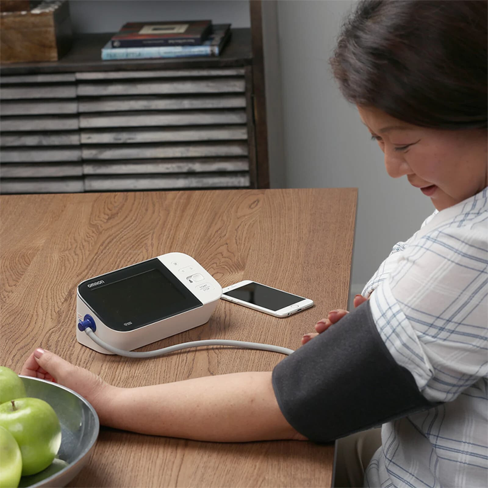 Woman taking blood pressure monitor at home