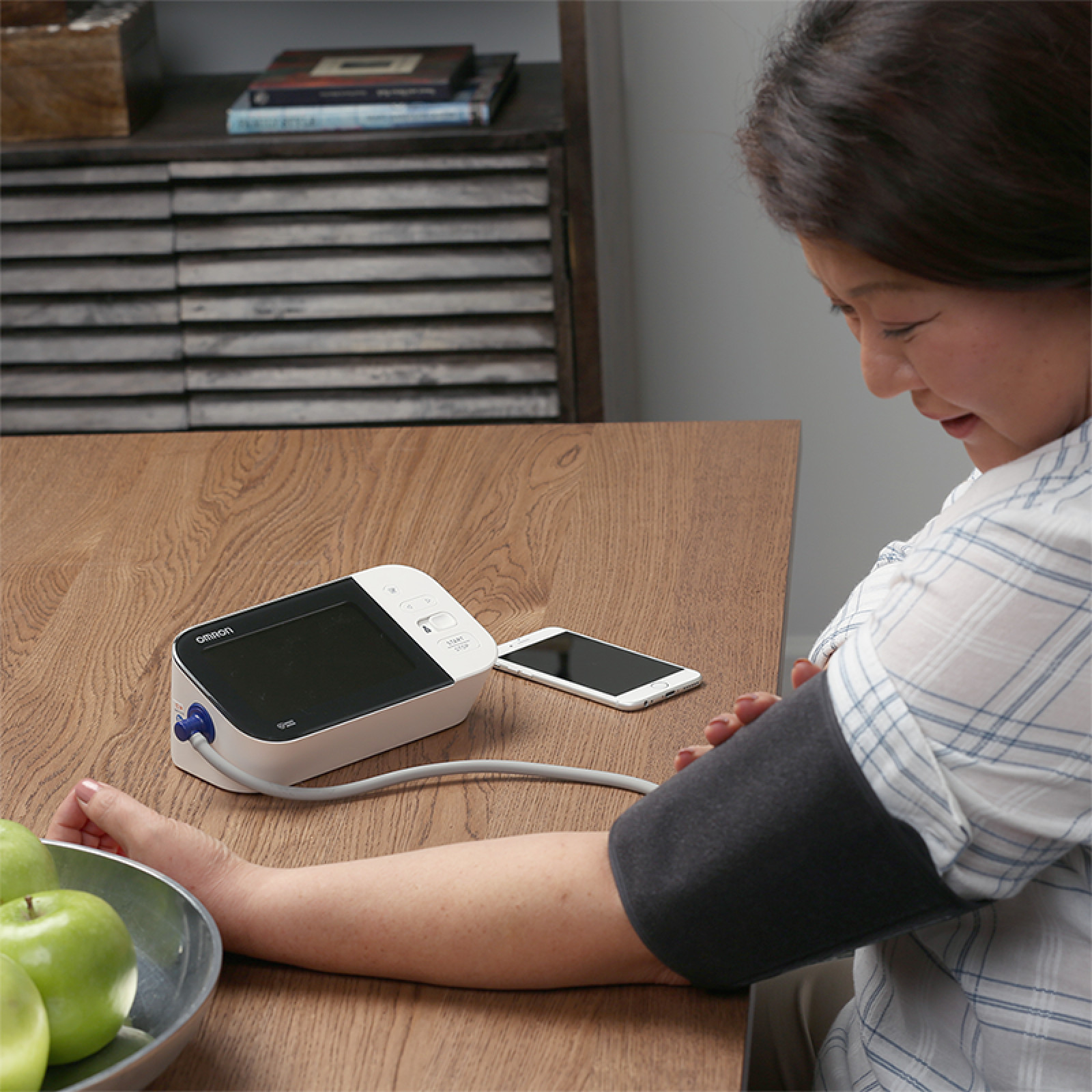 Woman taking blood pressure monitor at home