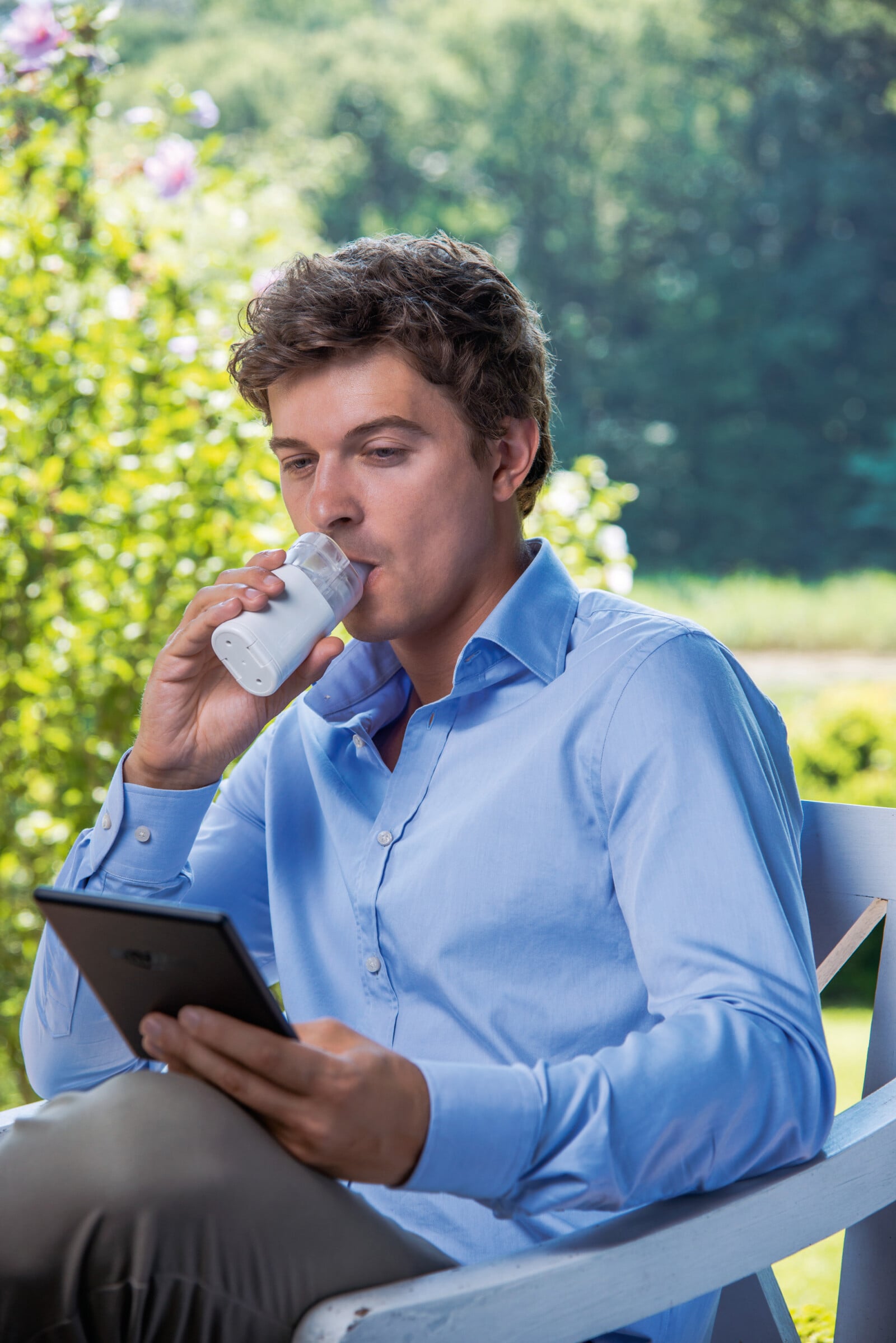 Man sitting in a chair outside using a nebulizer